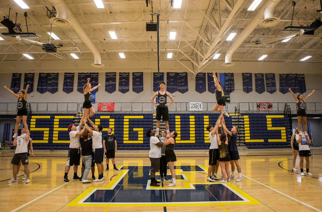 Everett High School cheerleaders and football players run through their full routine during rehearsal in the Everett High School gym on Sept. 26. (Olivia Vanni / The Herald)
