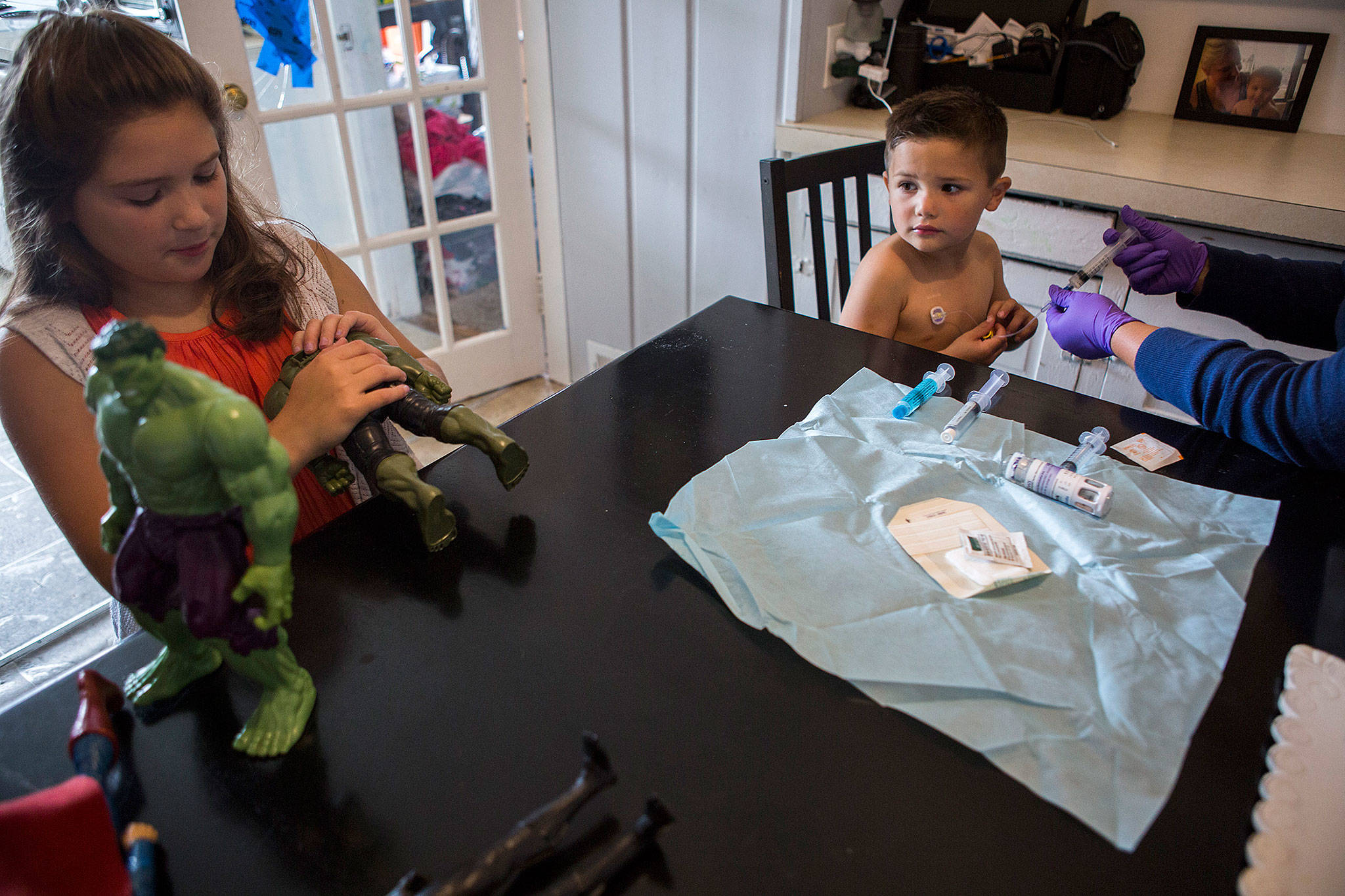 Samuel Avalos, 4, gets treatment for his hemophilia from his mother as his sister brings out some of his hulk action figures at their family’s home on Aug. 30 in Snohomish. (Olivia Vanni / The Herald)