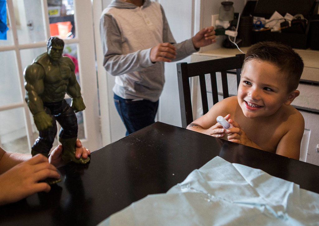 Samuel Avalos, 4, smiles as he tries to spray his sister with leftover saline in his treatment syringe at their family’s home Aug. 30 in Snohomish. (Olivia Vanni / The Herald)
