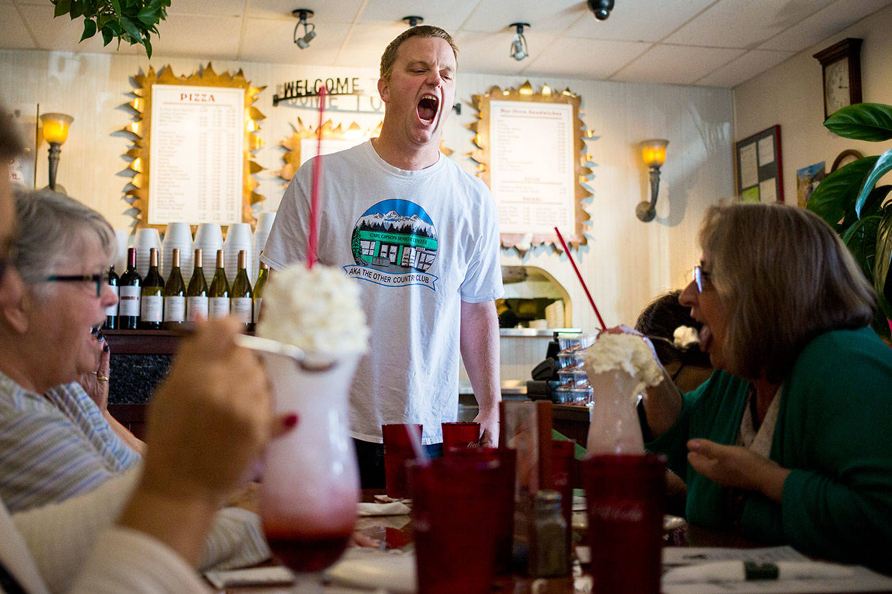 Program coordinator Eric Wollan dares Paula Darrow (right) to eat the whipped cream off her Italian soda like a shark during a group trip from the Everett Senior Center to Contos Pizza & Pasta on Sept. 17 in Lake Stevens. (Andy Bronson / The Herald)