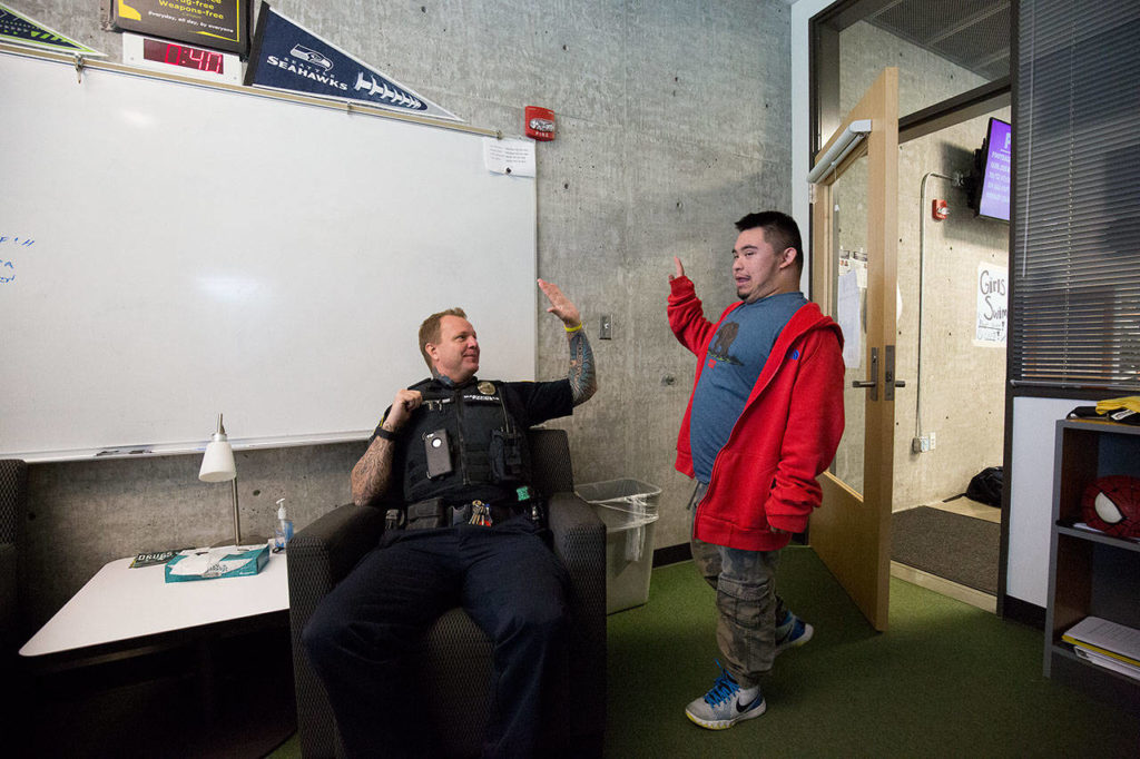 Marysville Pilchuck School Resource Officer Chris Sutherland gets a high five from Jorge Farias-Villalobos at Marysville Getchell High on Thursday. Villalobos had been a student at Marysville Pilchuck but was moved to Getchell. (Andy Bronson / The Herald)
