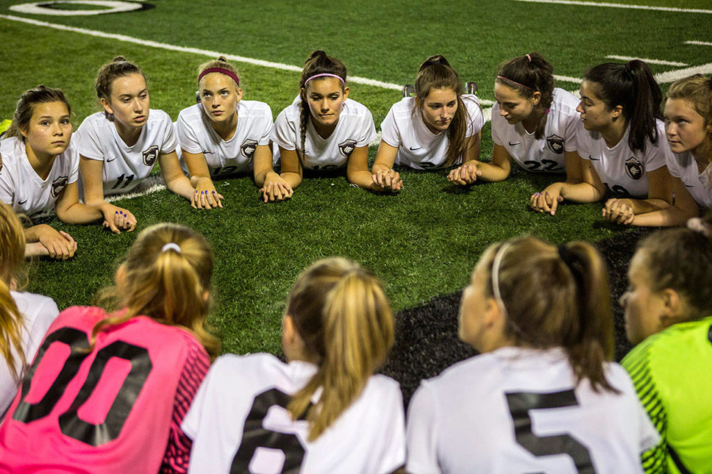 The Cedarcrest girls soccer team holds hands before a game against Snohomish on Sept. 25, 2018, in Snohomish. (Olivia Vanni / The Herald)
