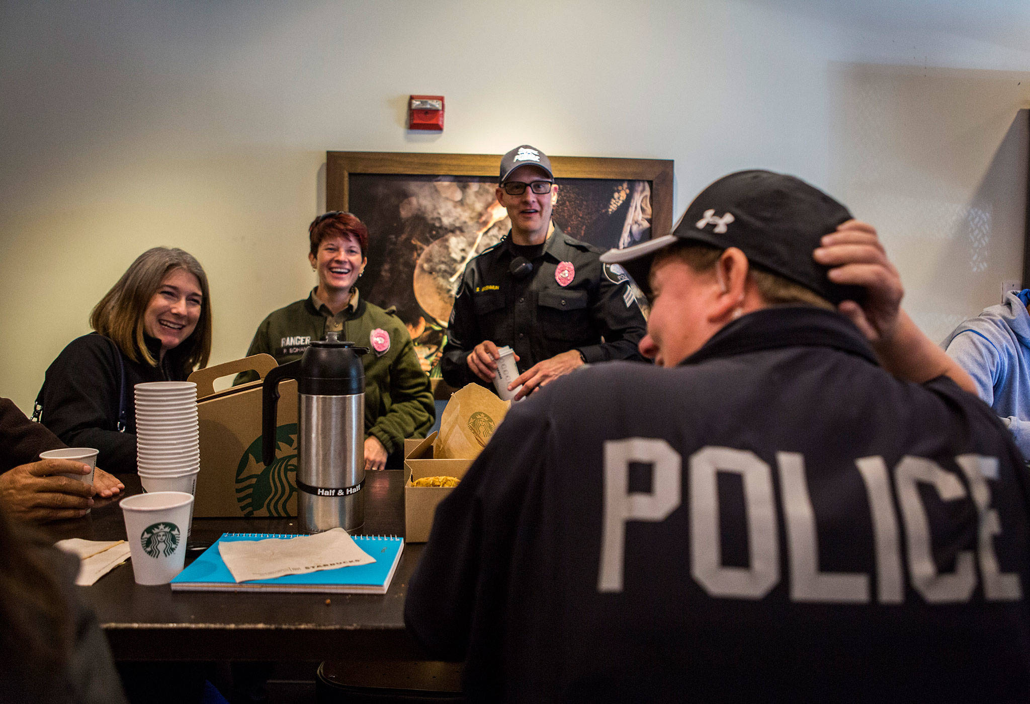 Nicole Kennedy, left, Ranger Peg Bohan and Sgt. Shaun Greenmun chat with the pink badges on during the Mukilteo Police Department’s Coffee with Mukilteo. (Olivia Vanni / The Herald)