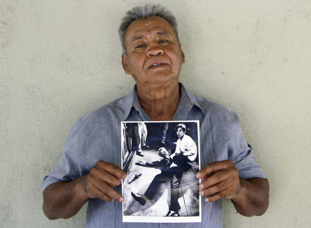 Juan Romero holds a Los Angeles Times photograph that shows Romero with Sen. Robert F. Kennedy at the Ambassador hotel in Los Angeles moments after Kennedy was shot. (Jud Esty-Kendall/STORYCORPS via AP, file)
