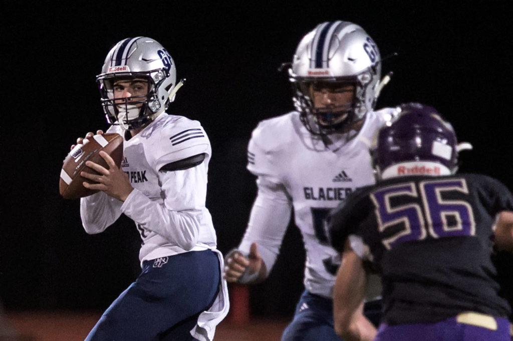 Glacier Peak’s Ayden Ziomas (left) looks for a receiver with teammate Ma’ake Fifita blocking Lake Stevens’ Jager Hill during a game on Oct. 8, 2018, at Lake Stevens High School. (Kevin Clark / The Herald)
