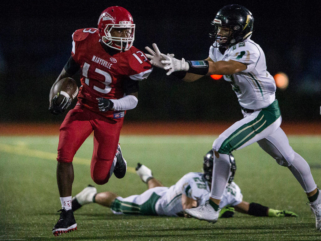 Marysville Pilchuck’s Bryan Sanders (left) evades a pair of Marysville Getchell defenders during the annual Berry Bowl rivalry game on Oct. 5, 2018, in Marysville. (Olivia Vanni / The Herald)
