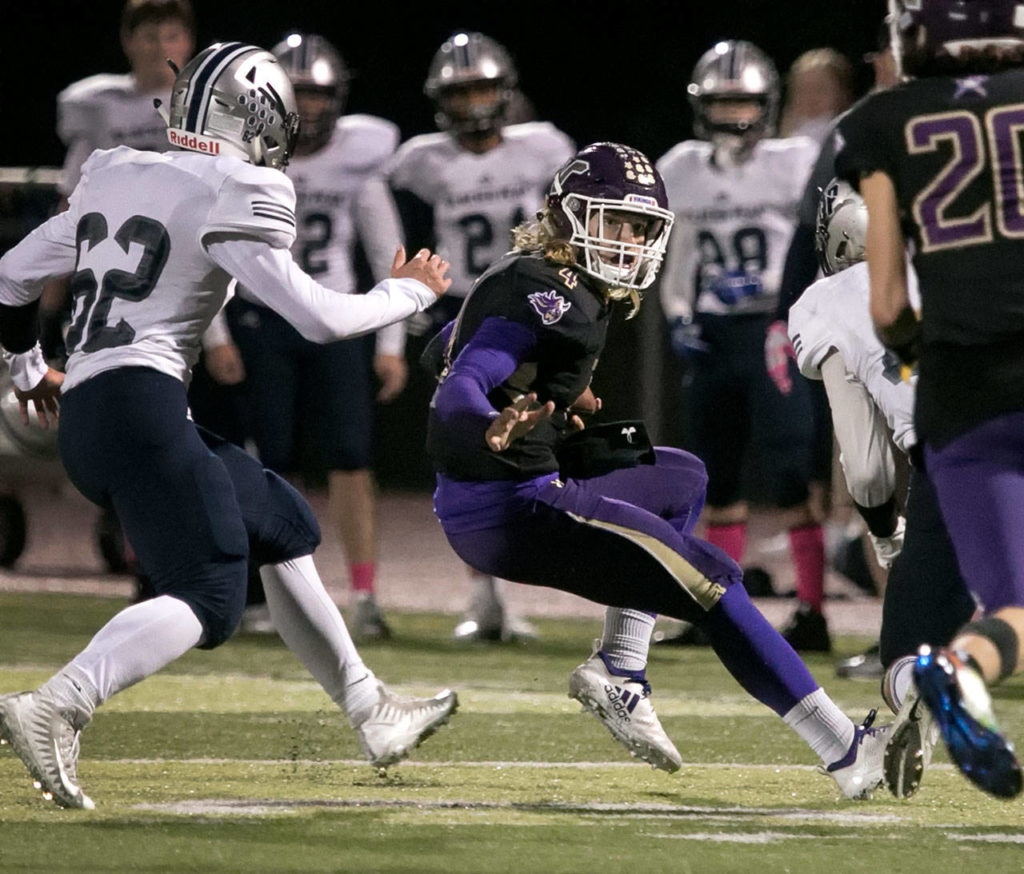 Lake Stevens’ Trey Long is chased out of the pocket by Glacier Peak’s Mitchell Harper Friday night at Lake Stevens High School on October 5, 2018. (Kevin Clark / The Herald)
