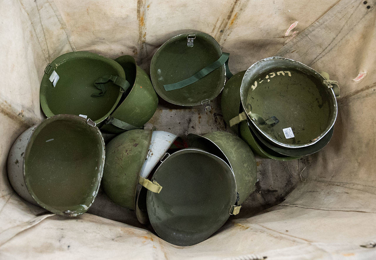 Army helmets sit in a bin at Ed’s Surplus & Marine in Lynnwood. (Andy Bronson / The Herald)