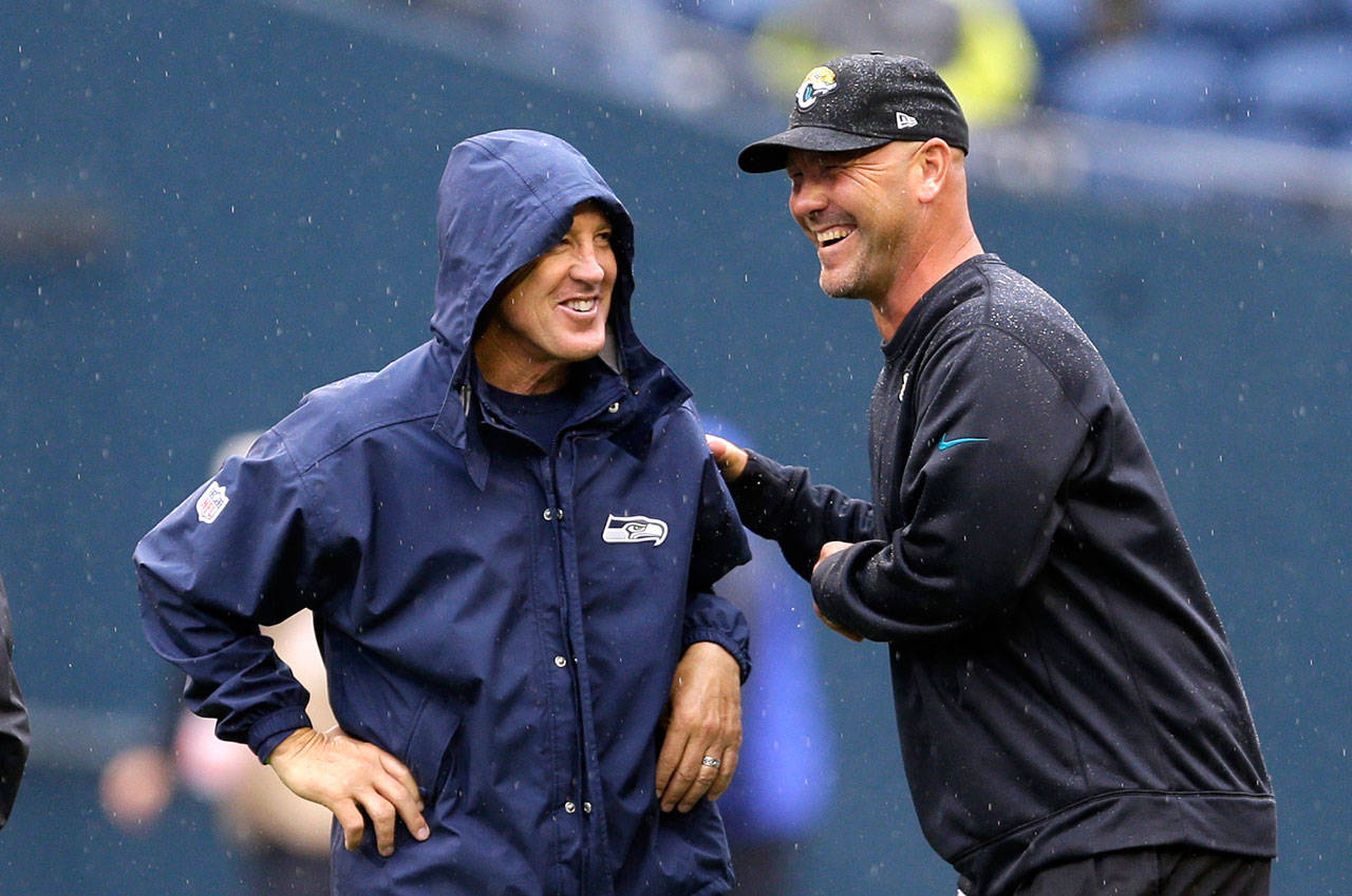 Seahawks head coach Pete Carroll (left) and former Jaguars head coach Gus Bradley talk in the rain before a game on Sept. 22, 2013, in Seattle. (AP Photo/Ted S. Warren)
