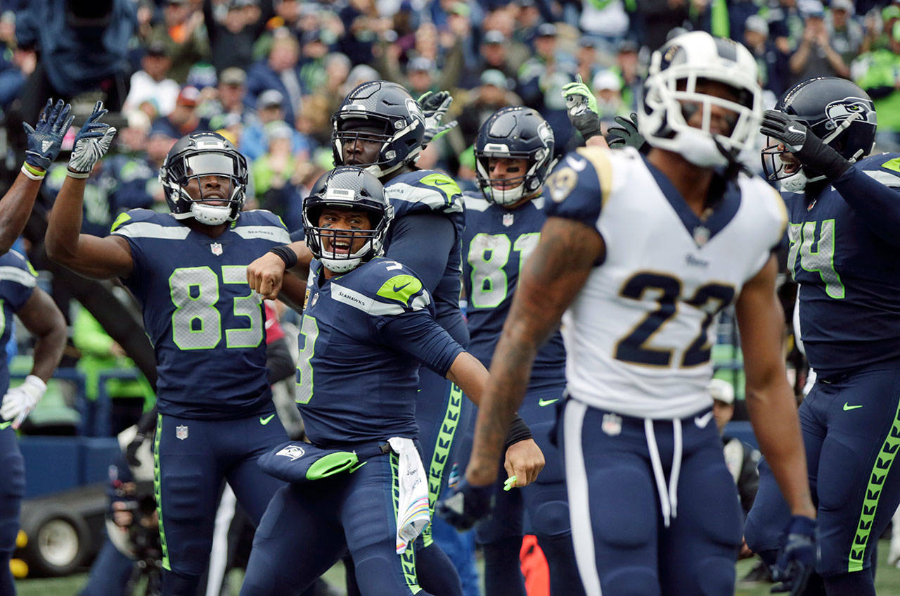 Seahawks quarterback Russell Wilson (3) celebrates next to Rams cornerback Marcus Peters (22) after Seahawks wide receiver David Moore (left) caught a pass for a touchdown during the second half of a game Oct. 7, 2018, in Seattle. (AP Photo/Scott Eklund)