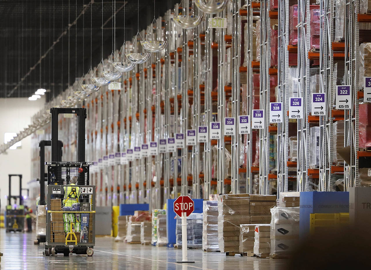 In this May 3 photo, an associate guides a vehicle past rows of goods during a tour of the Amazon fulfillment center in Aurora, Colorado. (AP Photo/David Zalubowski, File)