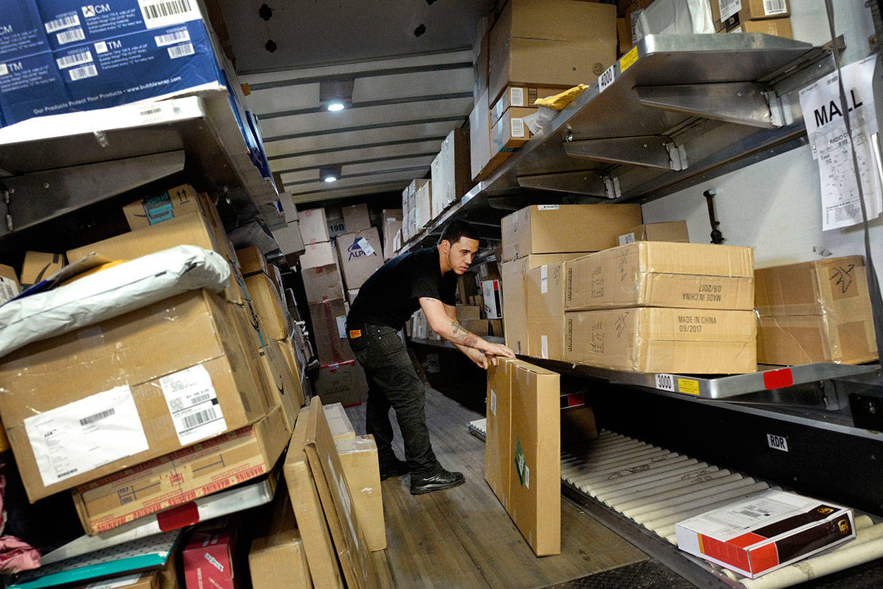 A UPS employee loads packages onto a truck at a company facility in New York in May 2017. The job market is the tightest it has been in nearly five decades and online shopping is still growing at a double-digit rate. Businesses now need more workers at a time when fewer are available. UPS plans to hold nearly 170 job fairs around the country on Oct. 19. (AP Photo/Mark Lennihan, File)