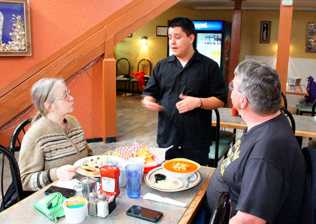 Noe Ochoa checks on how customers Bridget and Lyle Zimmerman are enjoying their meal. (Patricia Guthrie / Whidbey News-Times file)
