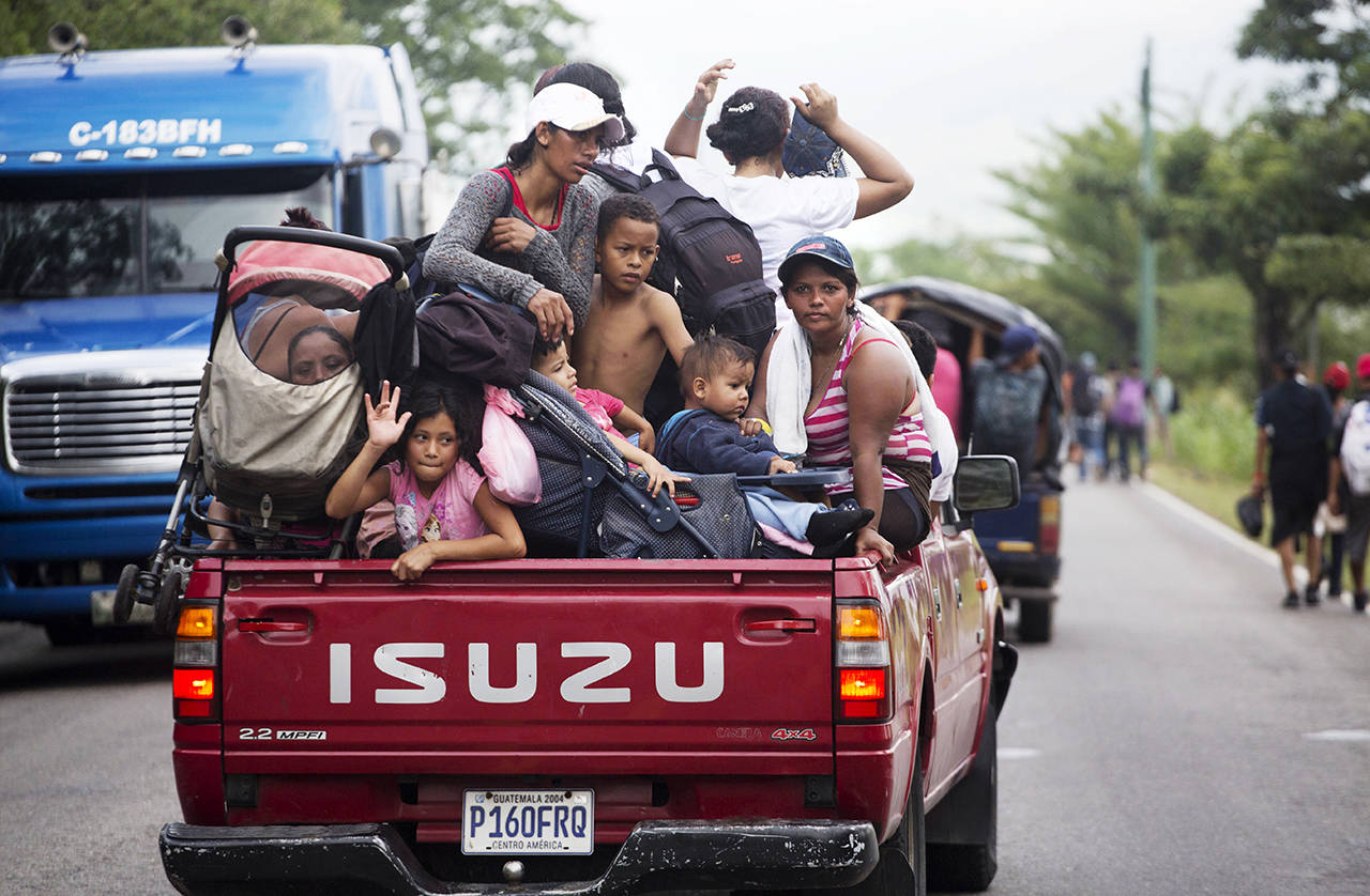Honduran migrants who are traveling to the U.S. as a group get a free ride in the back of a driver’s truck as they make their way through Zacapa, Guatemala on Wednesday. The group of some 2,000 Honduran migrants are hoping to reach the United States despite President Donald Trump’s threat to cut off aid to Central American countries that don’t stop them. (AP Photo/Moises Castillo)