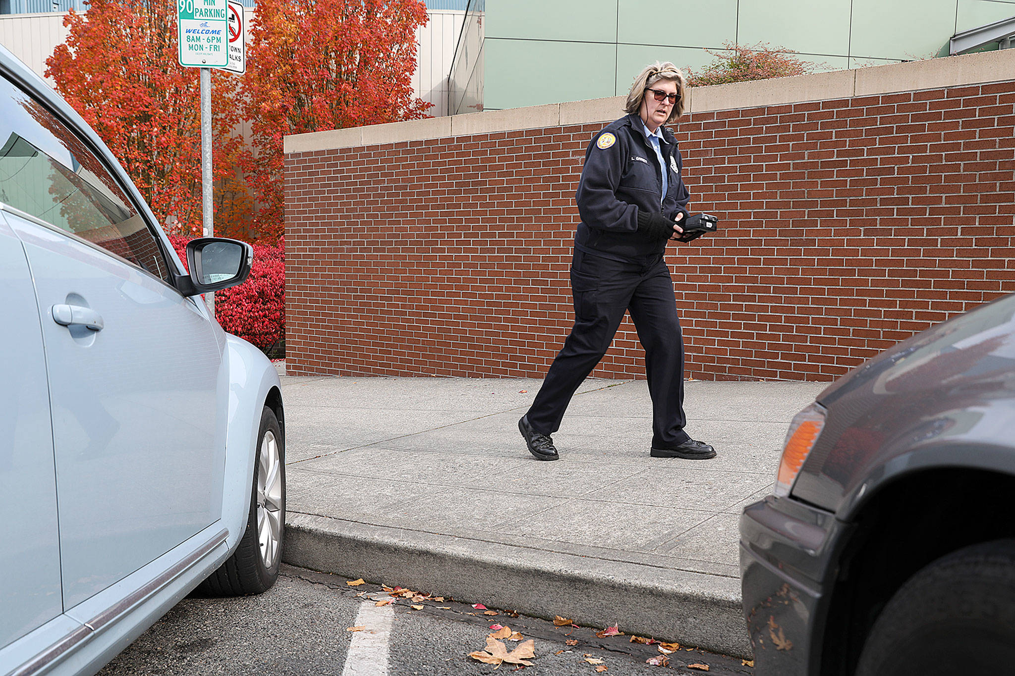 Currently, parking enforcement officers, like Lori Garrett pictured above, have to input license plate numbers manually into a handheld device to check if vehicles are overstaying the posted time limit. (Lizz Giordano / The Herald)