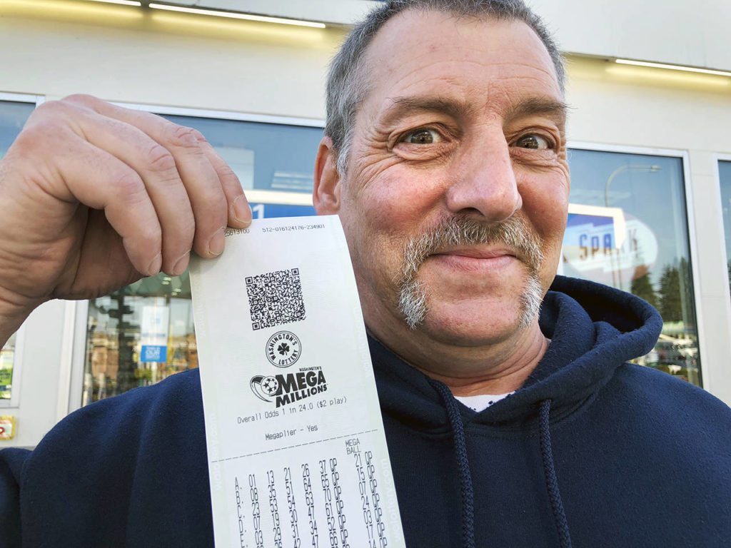 Jay Weaver of Everett holds tickets he bought Thursday at the Chevron station at Rucker Avenue and 41st Street. “Somebody’s got to win this. Why not me?” he said. (Andrea Brown / The Herald)
