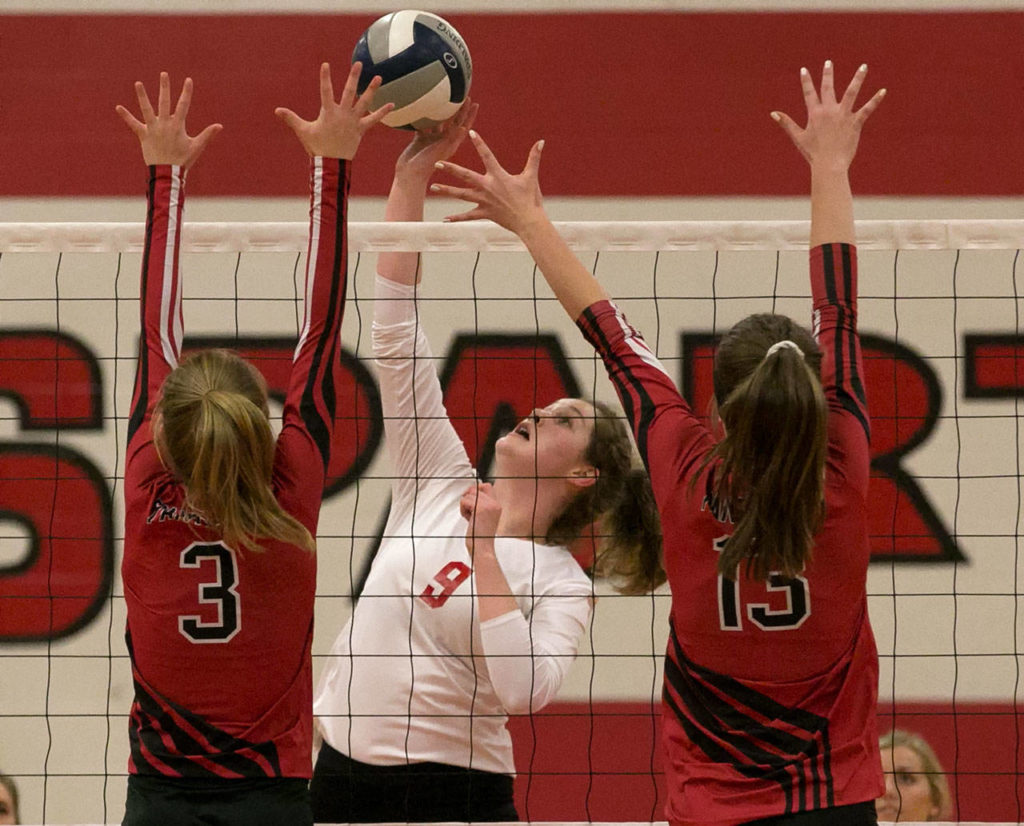 Stanwood’s Jordyn Foxen (center) attempts a kill with Snohomish’s Natalie Stern (left) and MacKenzie Whyte blocking Thursday at Stanwood High School. (Kevin Clark / The Herald)
