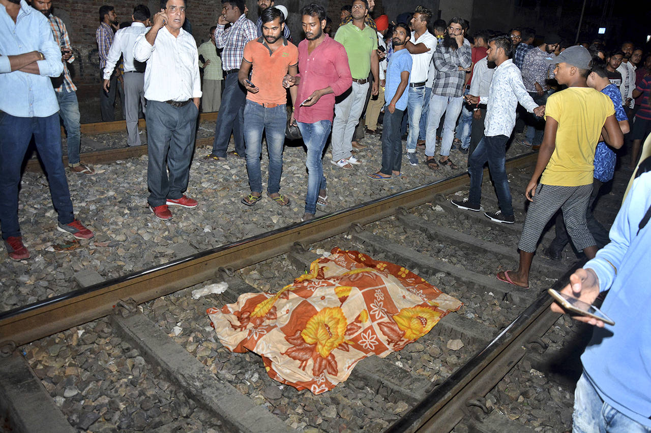 A body lies covered in cloth on a railway track in Amritsar, India, on Friday, after a speeding train ran over a crowd watching fireworks during a religious festival. (AP Photo/Prabhjot Gill)