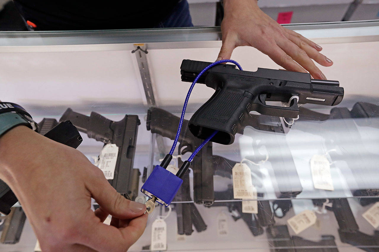 Gun shop owner Tiffany Teasdale demonstrates how a gun lock works on a handgun at her store in Lynnwood, Oct. 2. Voters in Washington state will decide the fate of an initiative that seeks to curb gun violence by toughening background checks for people buying semi-automatic rifles, increasing the age limit to 21 for buyers of those guns and requiring safe storage of all firearms. (Elaine Thompson/Associated Press)