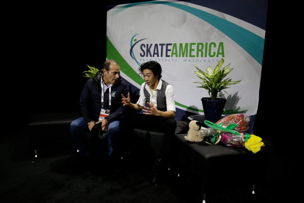 Nathan Chen talks to his coach while waiting for his score in the men’s short program at the 2018 Skate America competition Friday at Angel of the Winds Arena in Everett. (Andy Bronson / The Herald)

