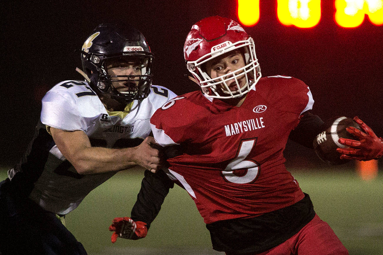 Marysville Pilchuck’s Dillon Kuk runs with Arlington’s Kristain Fairbanks attempting a tackle Friday at Quil Ceda Stadium in Marysville. (Kevin Clark / The Herald)