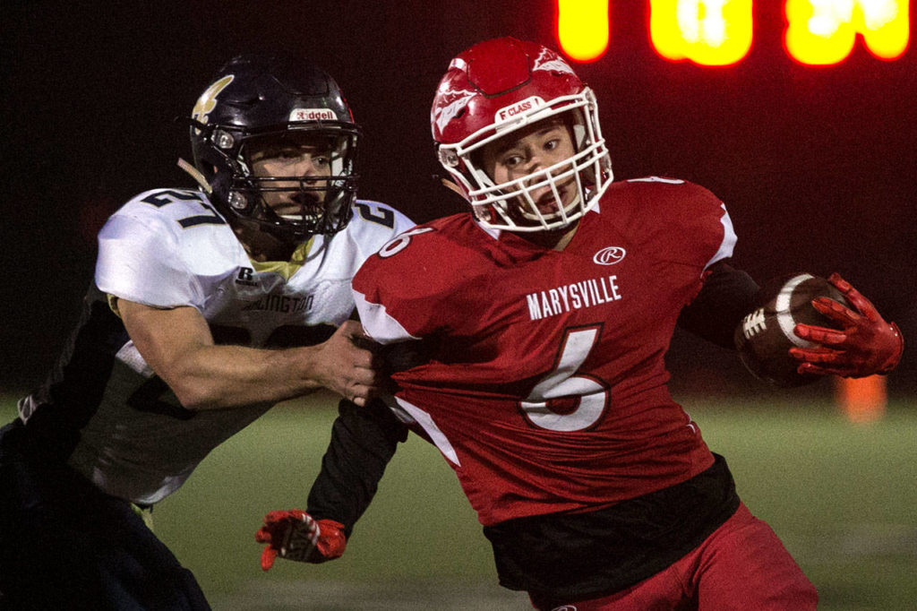 Marysville Pilchuck’s Dillon Kuk (right) carries the ball with Arlington’s Kristain Fairbanks attempting a tackle during a game on Oct. 19, 2018, at Quil Ceda Stadium in Marysville. (Kevin Clark / The Herald)
