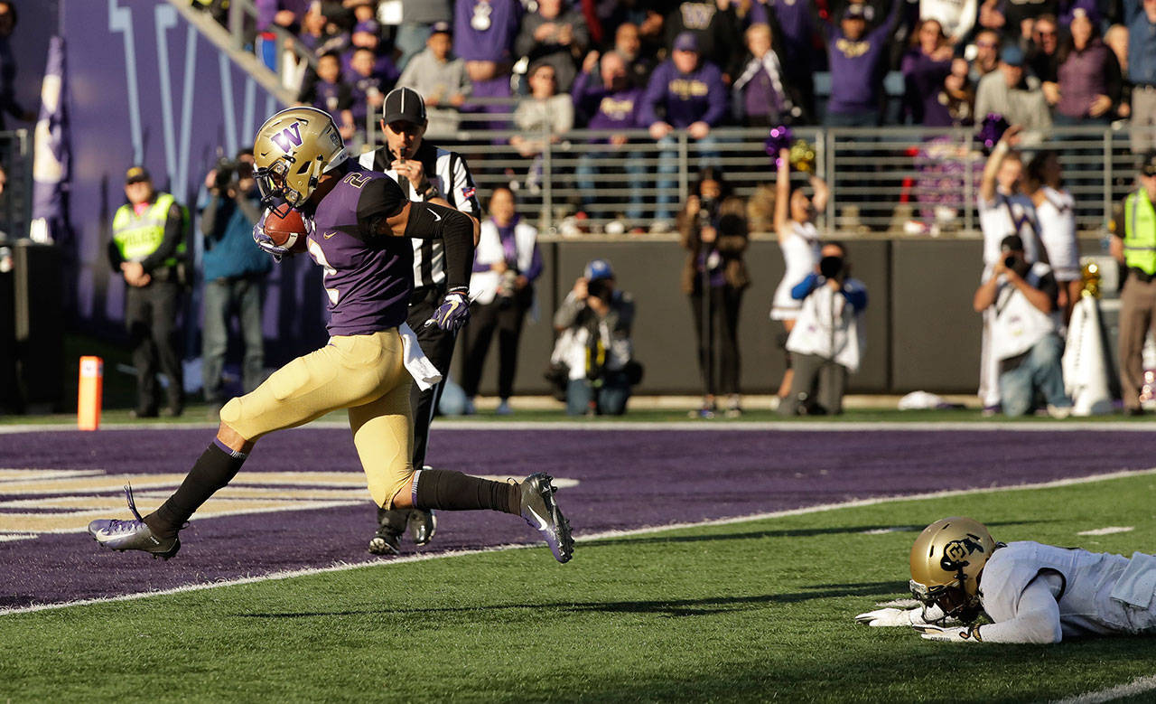 Washington wide receiver Aaron Fuller (left) scores a touchdown after evading Colorado cornerback Dante Wigleyk (right) during the second half of a game on Oct. 20, 2018, in Seattle. Washington won 27-13. (AP Photo/Ted S. Warren)