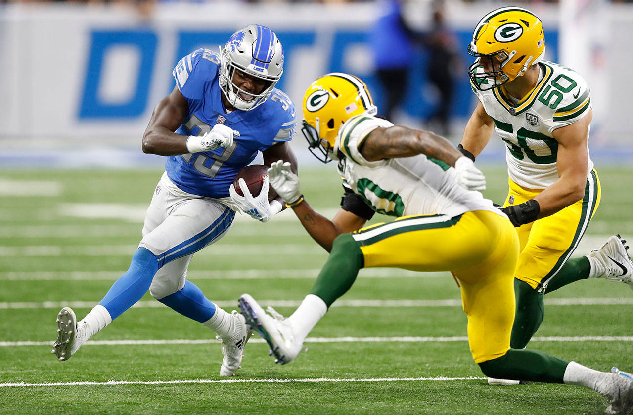Detroit’s Kerryon Johnson runs past Green Bay’s Kevin King (20) and Blake Martinez (50) during the first half of an Oct. 7 game in Detroit. (AP Photo/Carlos Osorio)
