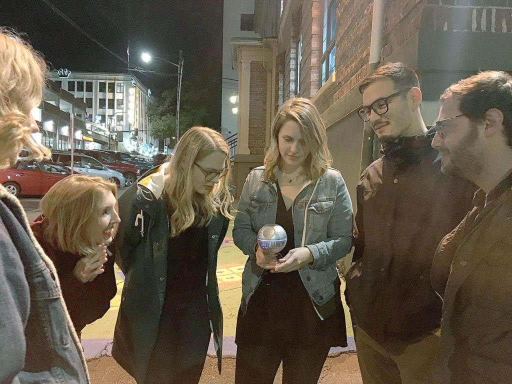 Gathered around a bluetooth speaker Friday, Oct. 26, Derek Johnston, Taylor Johnston, Emily Magley, Gabi Price, Alphonse Leopold, and Doug Evans listen to a walking tour of supposedly haunted places in Everett. (Ben Watanabe / The Herald)
