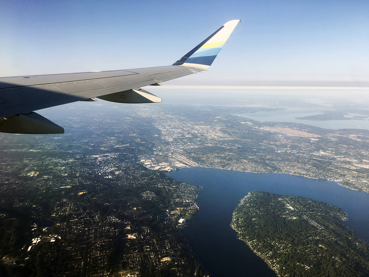 An Alaska Airlines plane begins its approach to Sea-Tac Airport (light area at right) over the eastern suburbs in July 2018. Mercer Island is at lower right. (Sue Misao / Herald file)