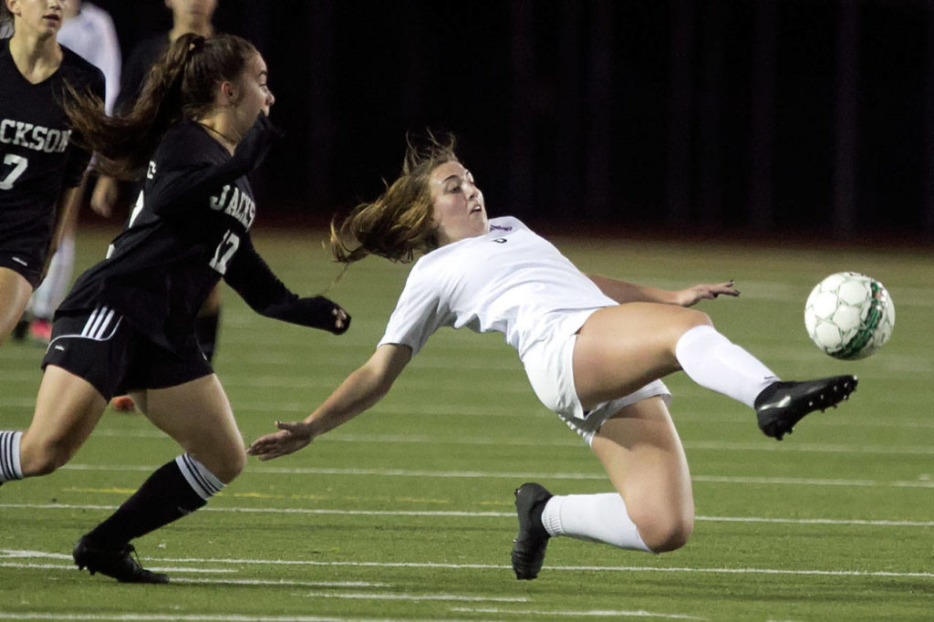 Lake Stevens’ Samantha Foley (right) tries to clear the ball as Jackson’s Natalie Hawkins (left) trails during a Wesco 4A match Thursday at Everett Memorial Stadium. (Kevin Clark / The Herald)

