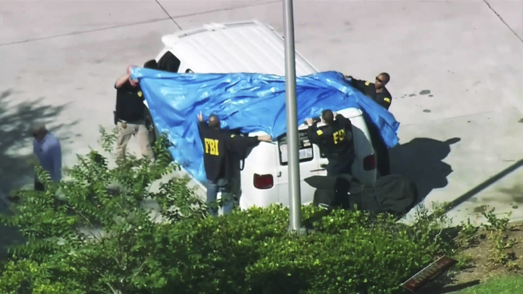 In this frame grab from video, FBI agents cover a van parked in Plantation, Florida, on Friday, that federal agents and police officers have been examining in connection with package bombs that were sent to high-profile critics of President Donald Trump. The van has several stickers on the windows, including American flags, decals with logos and text. (WPLG-TV via AP)
