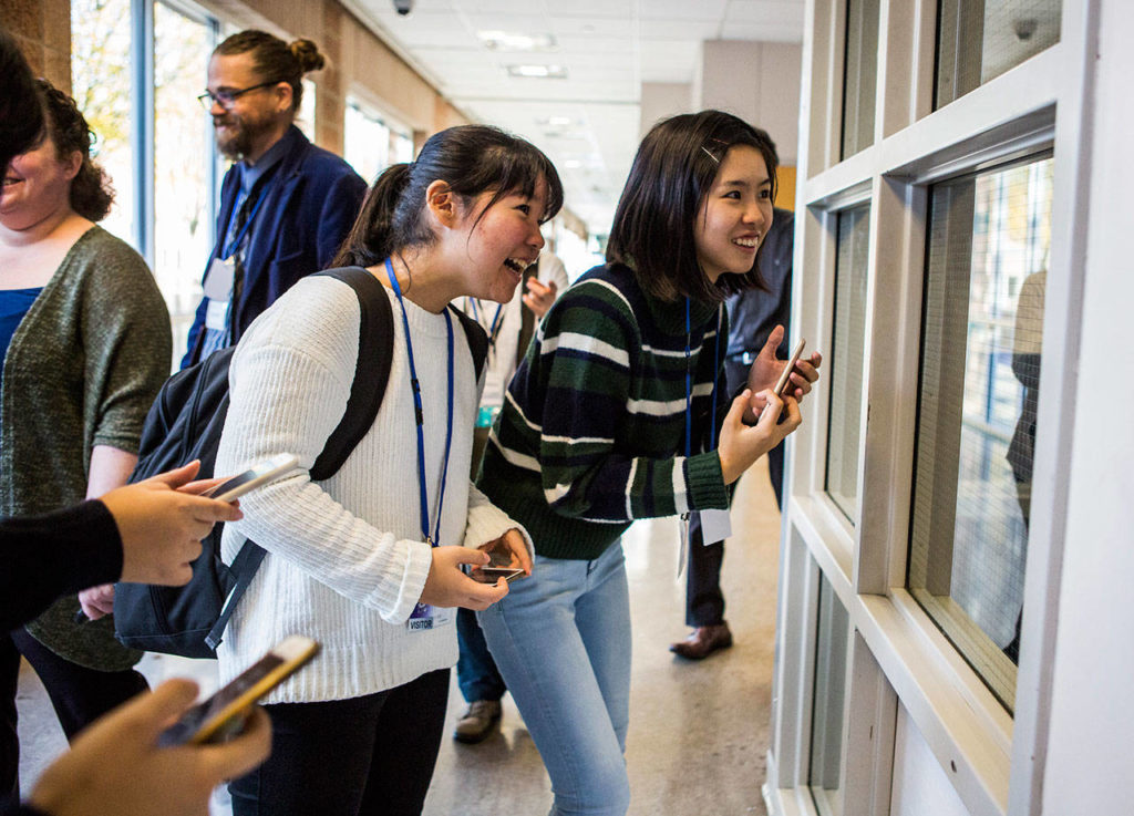 Airi Sugimoto (left) and Erika Okuma (right) look into the weight room during their tour of Kamiak High School. (Olivia Vanni / The Herald)
