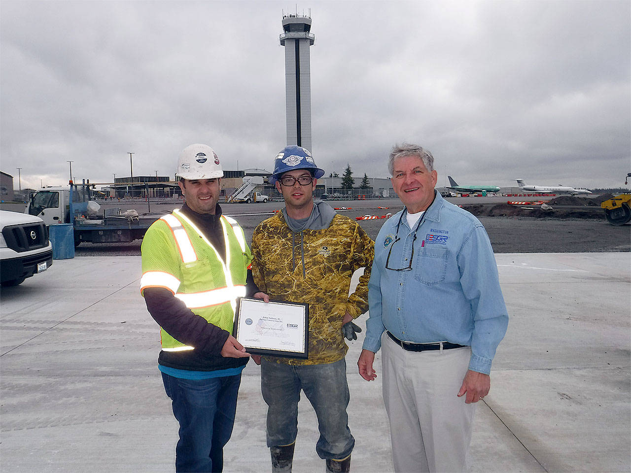 John Salinas II of Salinas Construction of Mukilteo (left) accepts the Employer Support of the Guard Reserve Patriot Award from employee Donny Passey (center) and ESGR’s John Van Dalen at the site of a new taxiway and aircraft parking ramp the company is building within view of the control tower at Paine Field. (Contributed photo)