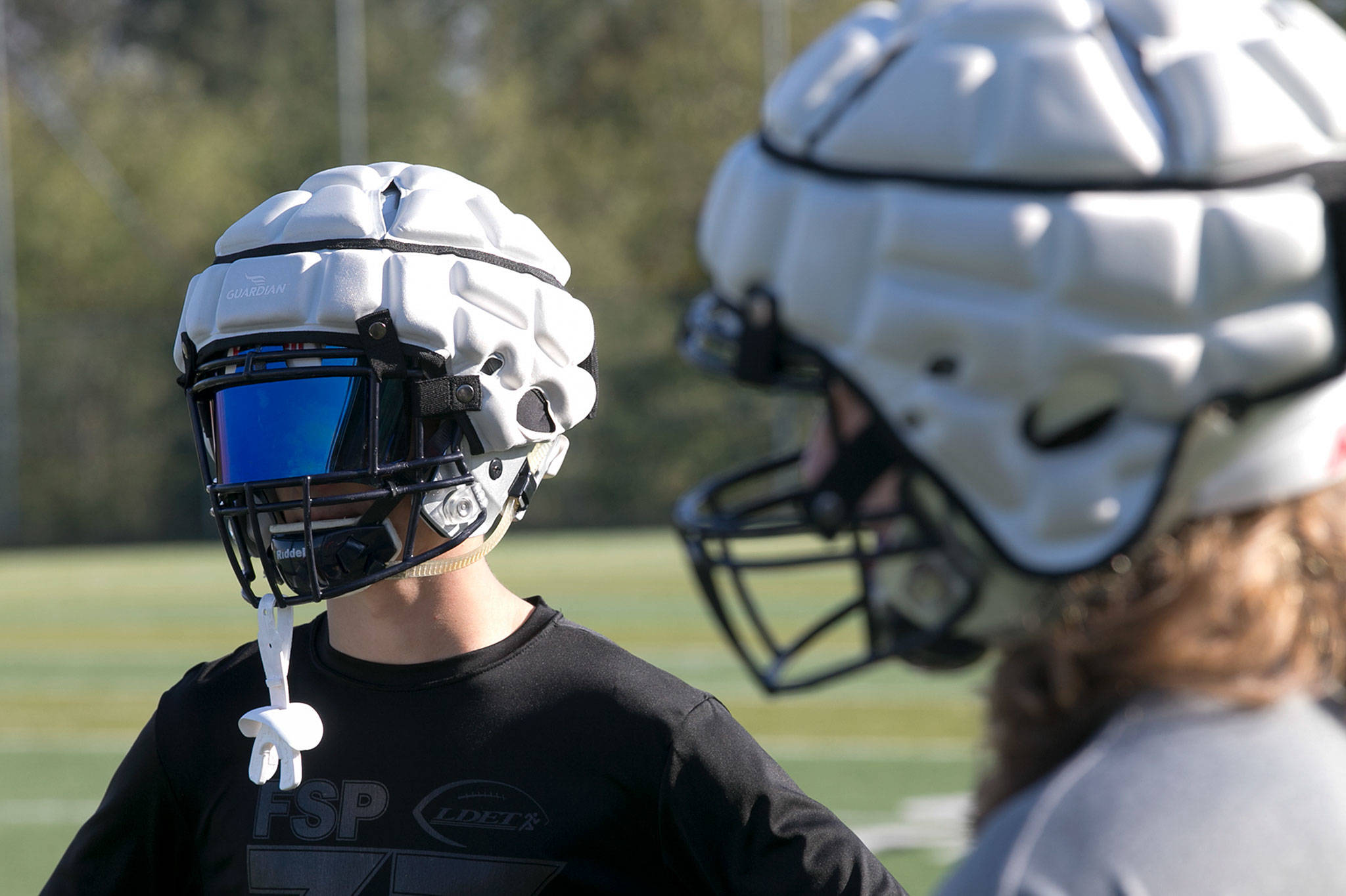 A face mask adds to the alien look as a pair of football players wear Guardian Caps on their helmets Thursday afternoon during practice at Glacier Peak High School in Snohomish on October 4, 2018. (Kevin Clark / The Herald)