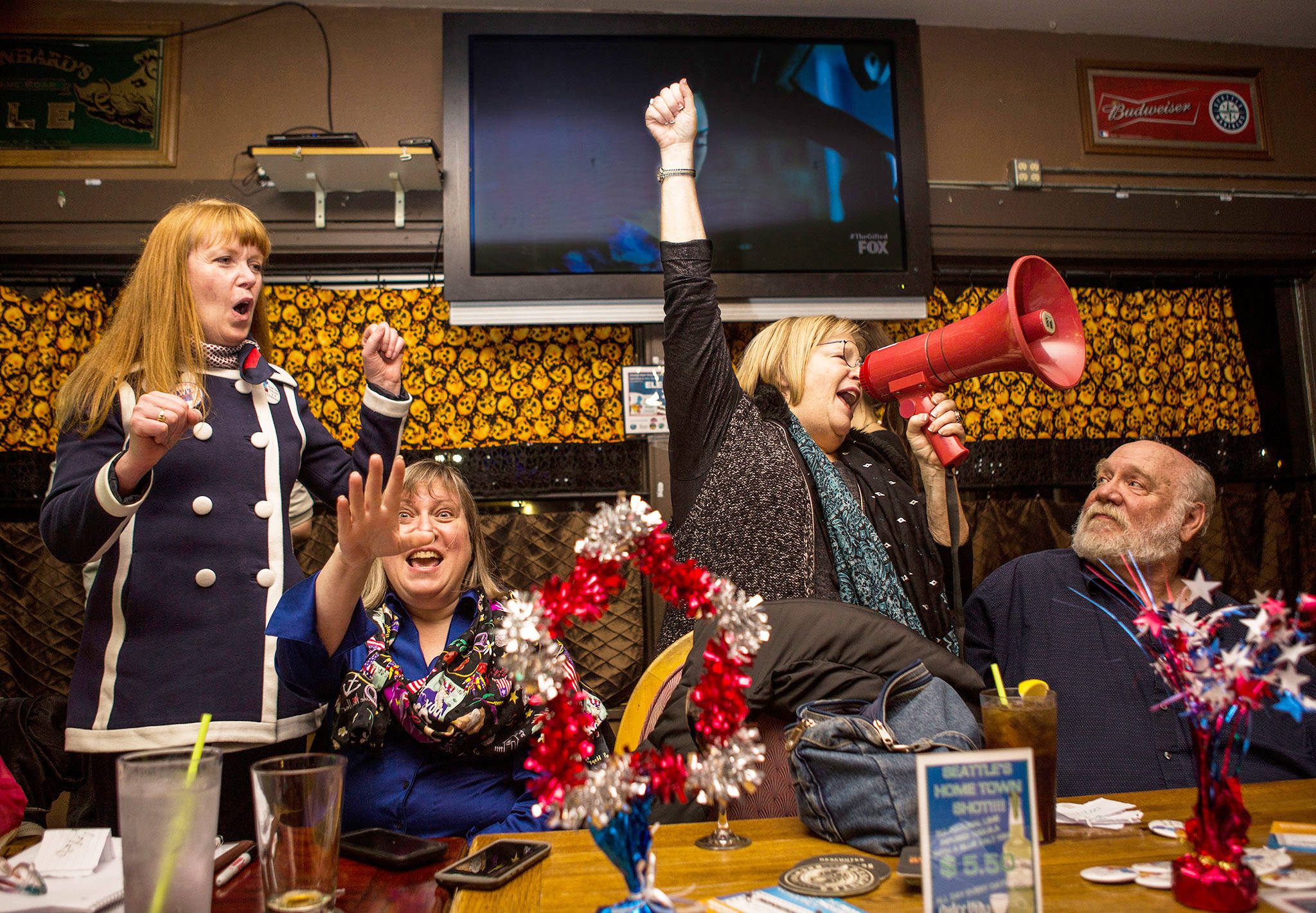 Everett Districts Now! supporters Paula Townsell (left), Beth Townsell (center lef), Diane Clausen (center right) and Daniel Clausen (right) react to the first polling numbers favoring the districts at during election night at the White Buffalo Saloon on Tuesday in Everett. (Olivia Vanni / The Herald)