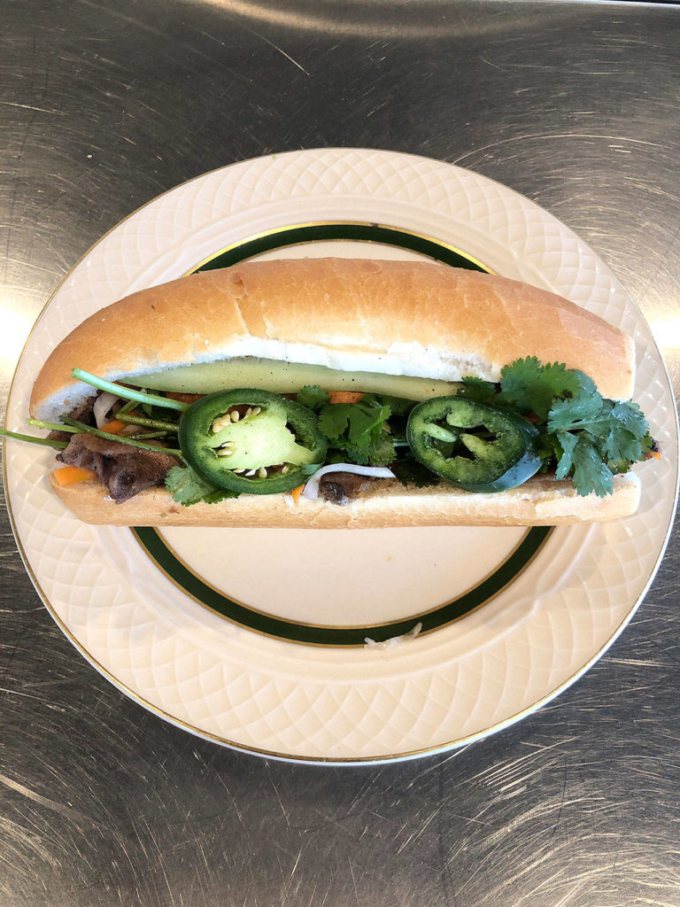 The binh mi sandwich at Basil includes grilled pork, pickled onion, pickled carrots, cucumbers, jalapeno, cilantro, butter and house-made marinade served on baguette bread. (Andrew Pham)
