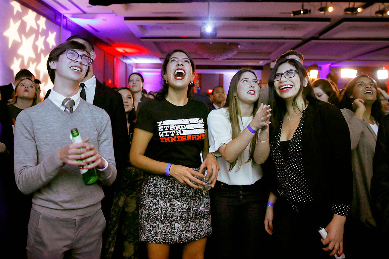 From left, Jed Bush, 24, of Washington, a Capitol Hill staffer; Maria Praeli, 25, a DACA recipient; and Katie Aragon, 26, react to Democratic wins in the House of Representatives during a Democratic party on Tuesday in Washington, D.C. (AP Photo/Jacquelyn Martin)