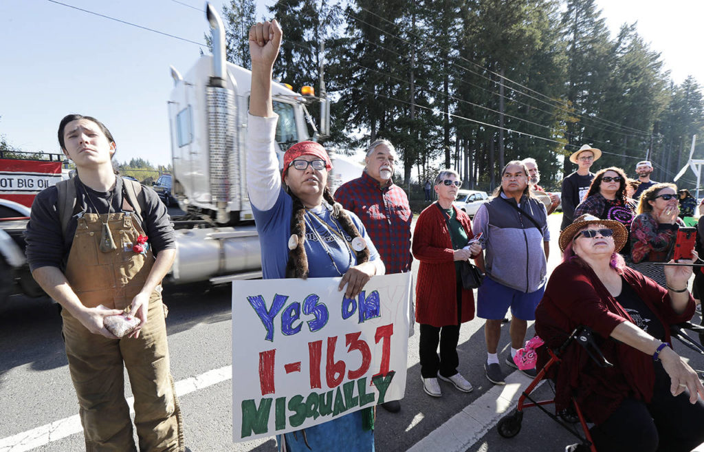 In this Oct. 17 photo, a supporter of Initiative 1631 holds a sign referencing the Nisqually Indian Tribe during a rally supporting I-1631. (AP Photo/Ted S. Warren, File)
