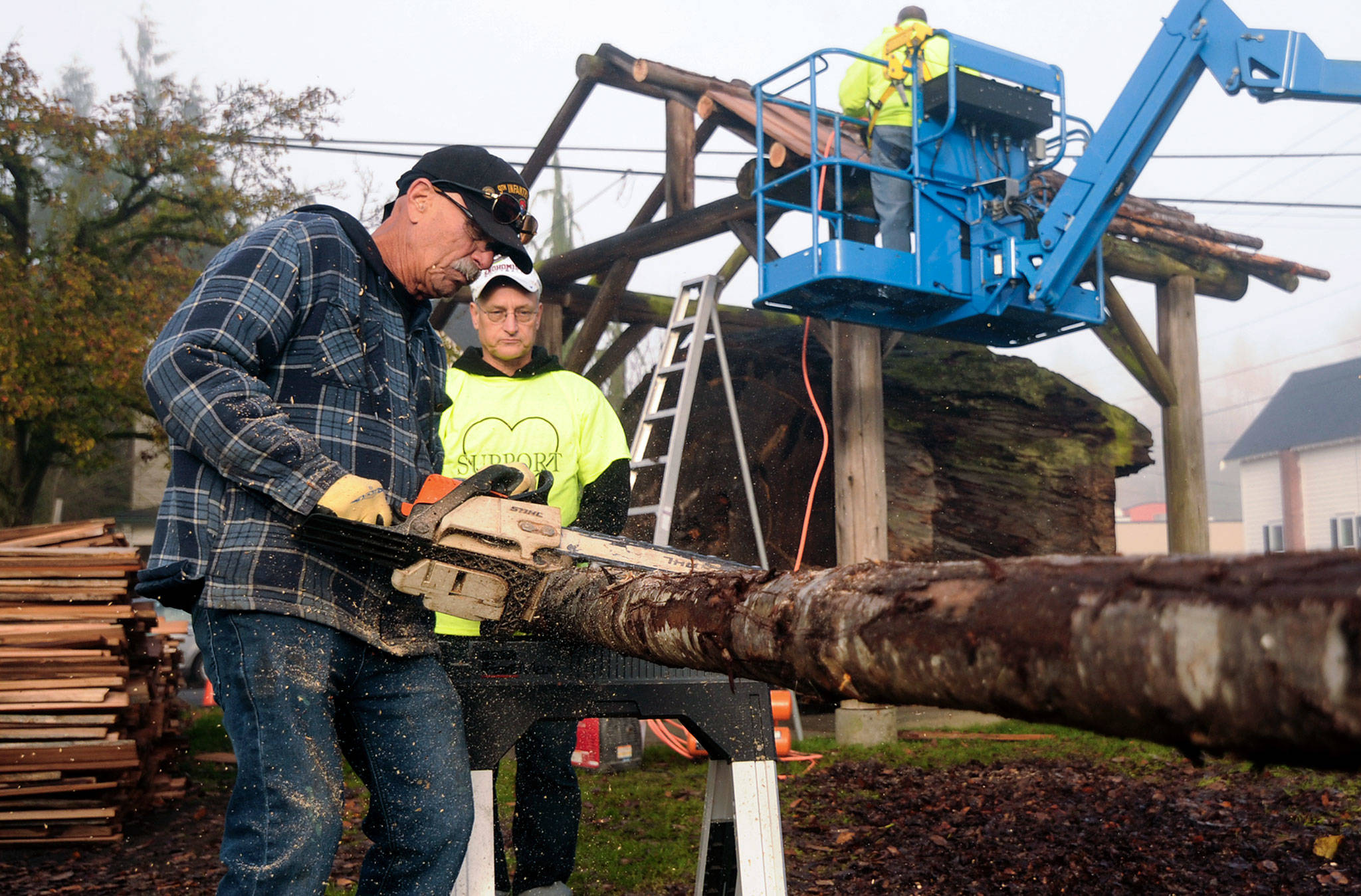 Steve Bates, of Snohomish, uses a chain saw to carve a groove into a log that will become one of the rafters as he and members of the Snohomish Carnegie Foundation tackle the job of replacing the shelter roof over the 1940 Lervick log that has been on display in front of the Carnegie library building on Saturday. (Doug Ramsay / For The Herald)