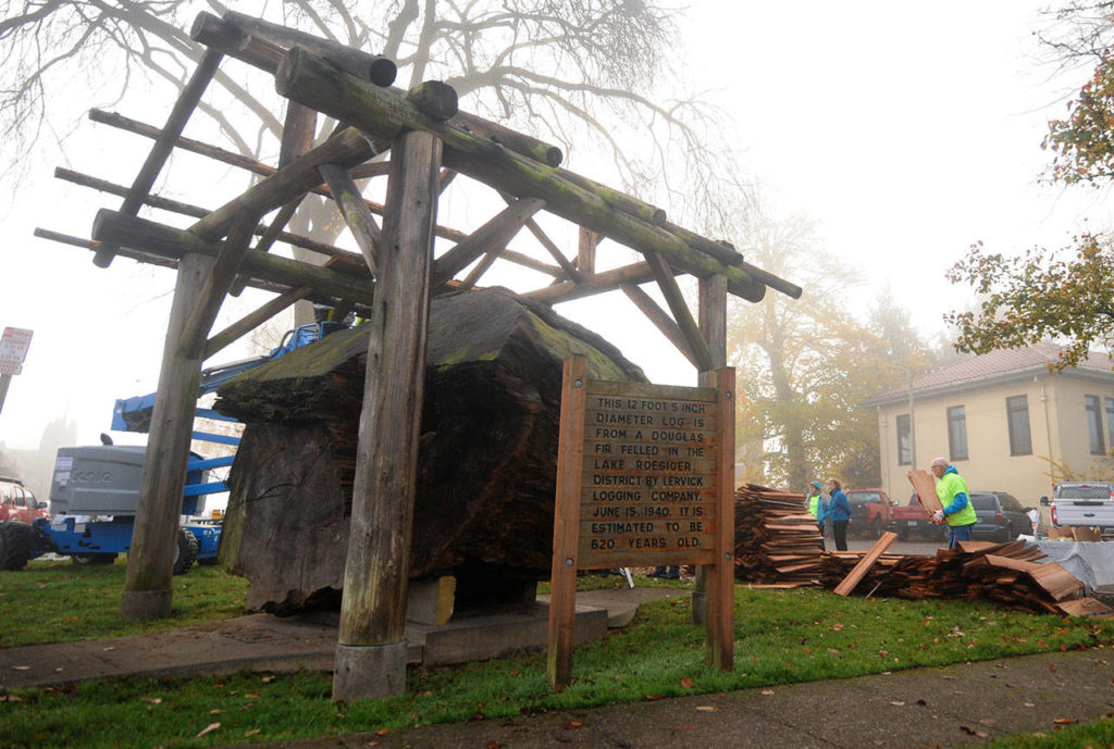 The fog lingers over downtown Snohomish as a work party from the Snohomish Carnegie Foundation tackle the job of replacing the shelter roof over the 1940 Lervick log that has been on display in front of the Carnegie library building on Saturday. (Doug Ramsay / For The Herald)
