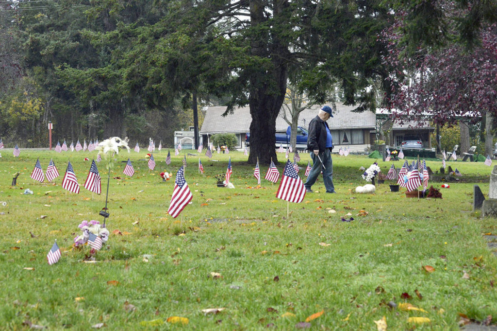 Ed Hickey walks among the many flags planted near the graves of veterans at Maple Leaf Cemetery in Oak Harbor. Hickey, other members of the Oak Harbor Military Officers Association of America and NJROTC volunteers placed over 500 flags across the island. (Laura Guido/Whidbey News-Times)
