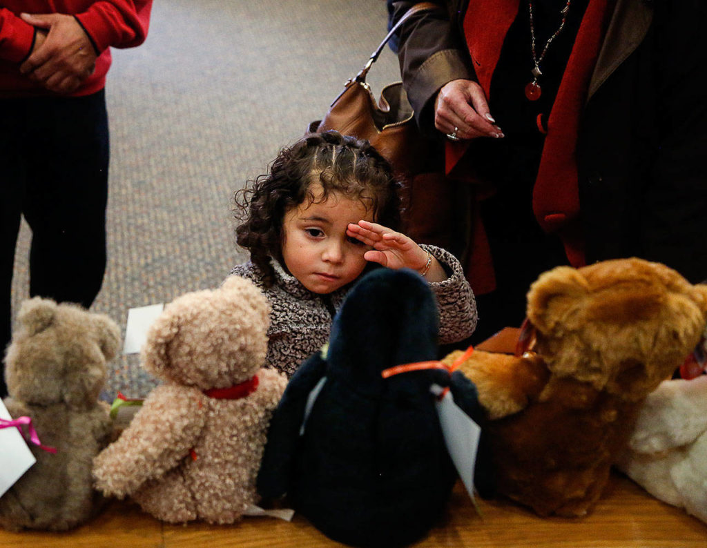 As her adoptive parents and others watch, Fernanda Yaresli Gonzales-Martinez tries to pick out a stuffed animal from a variety of them lined up on the rail of the jury box in Judge David Kurtz’s courtroom, following her adoption proceedings Friday at Snohomish County Superior Court’s National Adoption Day. (Dan Bates / The Herald)

