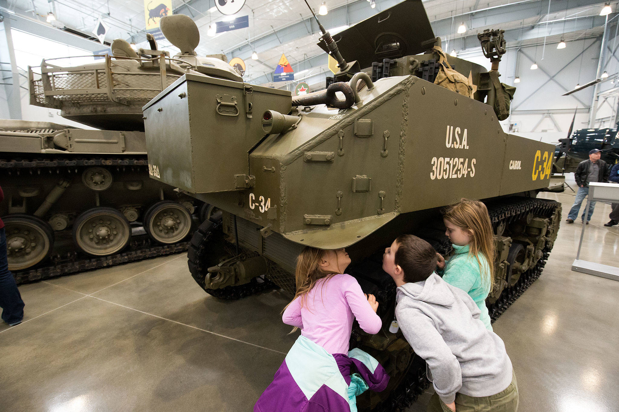 Eli Spaun, 5, Vin Capelli, 7, and Zoe Spaun, 7, right, peer at the underside of a M5A1 Stuart Light Tank in the new 30,000-square-foot hangar at the Flying Heritage & Combat Armor Museum at Paine Field on Saturday, Nov. 10, 2018 in Everett, Wa. The new hangar allows visitors a closer and touchable engagement with the museum’s armored vehicles. (Andy Bronson / The Herald)