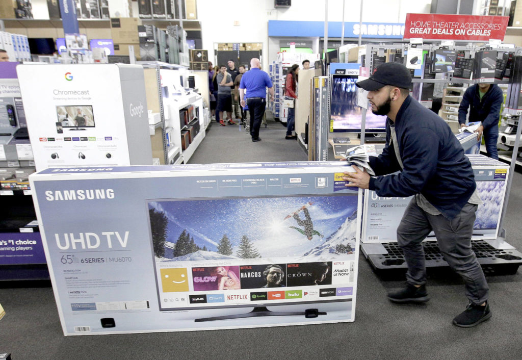 Jesus Reyes pushes a television down an aisle as he shops at a Black Friday sale at a Best Buy store in Overland Park, Kansas a year ago. (Associated Press file photo / Charlie Riedel)
