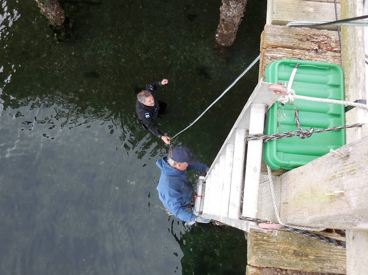 Garry Heinrich of Orca Network climbs down a ladder to join Florian Graner of SeaLife Productions to check underwater listening equipment installed near the wharf at Bush Point, Whidbey Island. (Contributed photo)