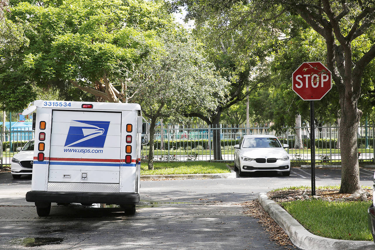Elston Bradshaw, a mail carrier for the United States Postal Service, drives away after delivering mail to an apartment complex in Aventura, Florida. (AP Photo/Brynn Anderson, file)