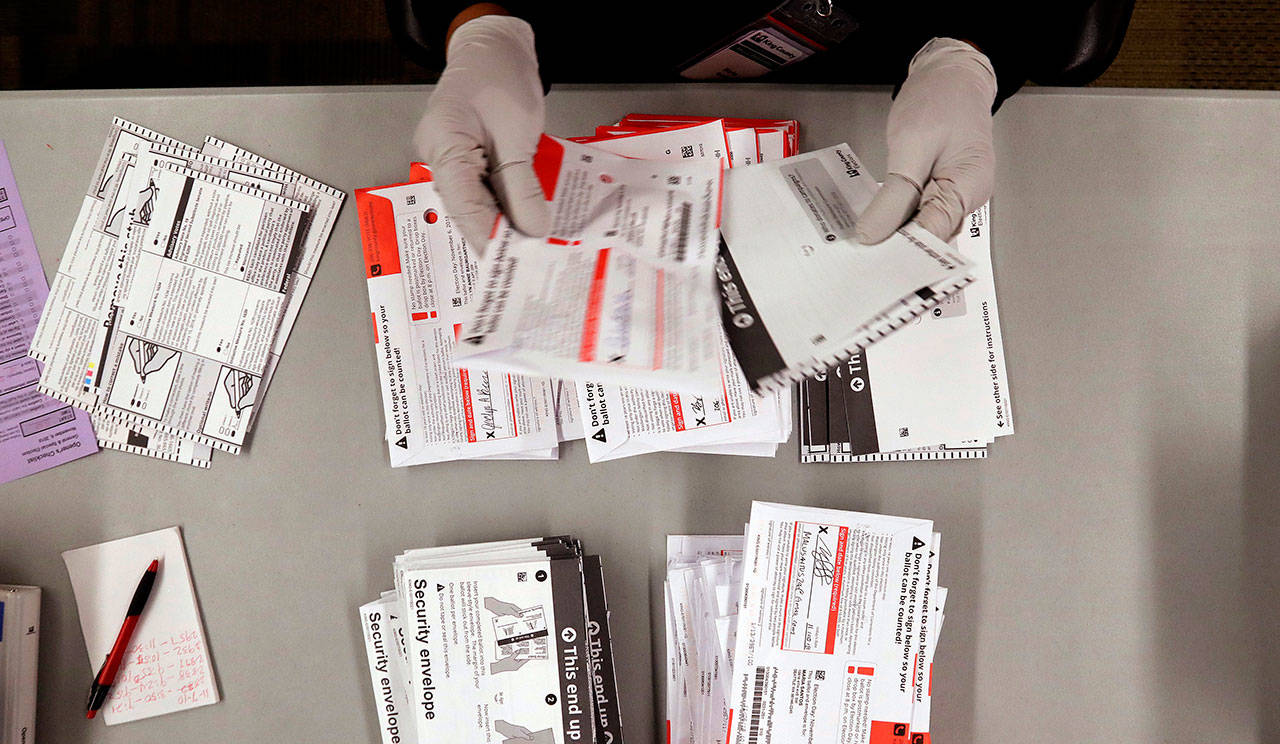 An election worker separates ballots from security envelopes at the King County Elections office on Nov. 7 in Renton. About 120,000 ballots statewide remain to be counted as of Wednesday. (Elaine Thompson/Associated Press)