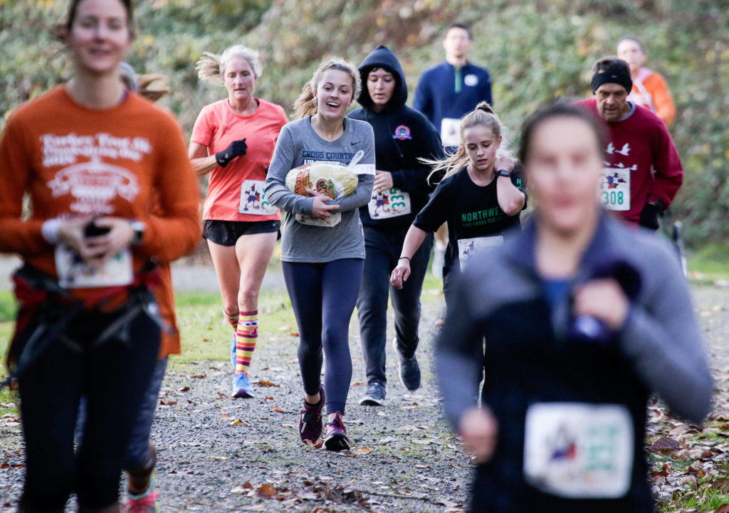 Finding two along the course, Brooklyn Hill and Katie Clark run with frozen turkeys during the Turkey Trot 5K on Thursday, Nov. 22, 2018 in Arlington, Wa. Runners could keep the turkey if they finished the race with it in hand. (Andy Bronson / The Herald)
