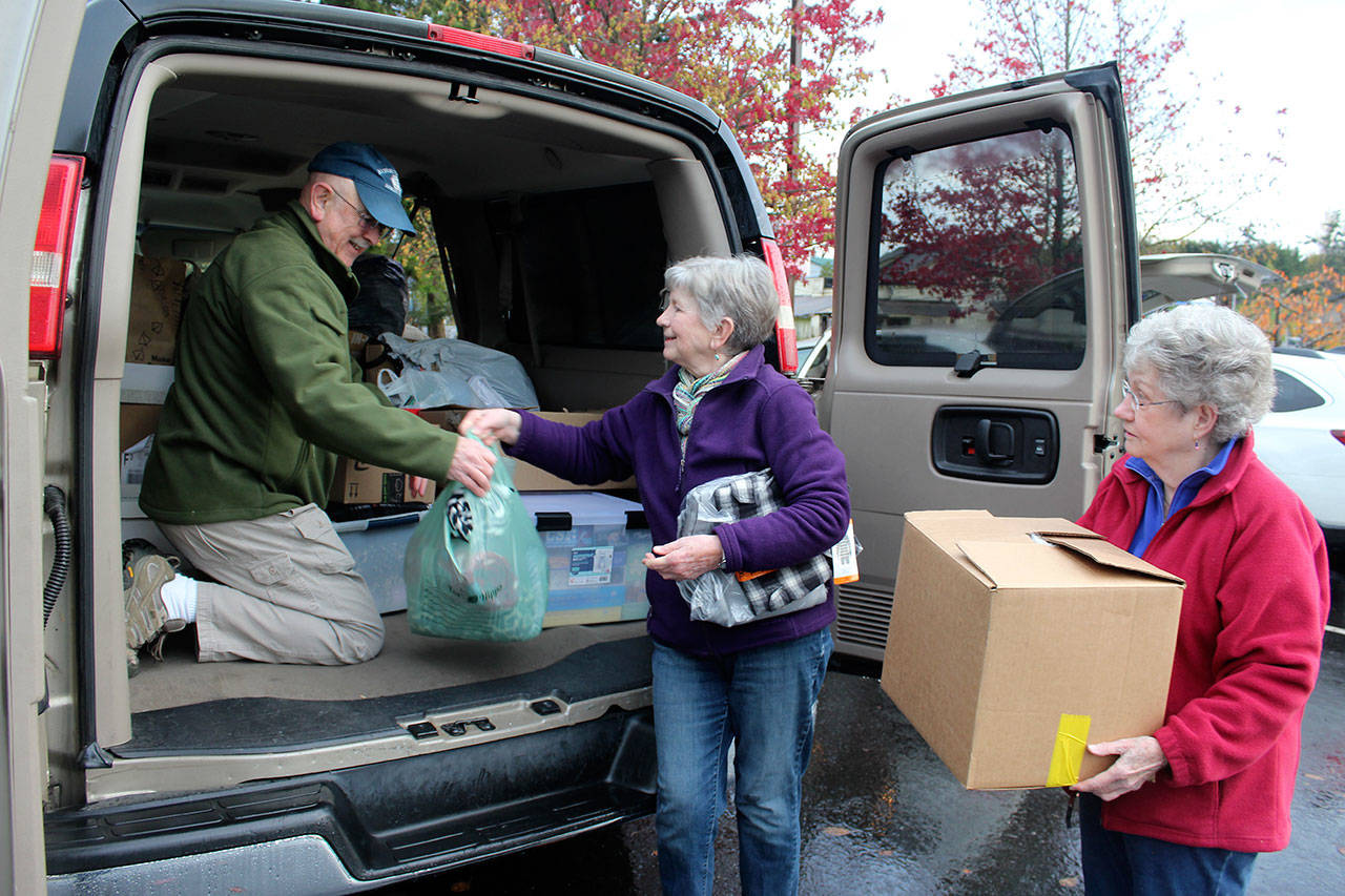Tony Aguilar arranges donations handed to him by Jean Beers (center) and Norma Hansson. (Patricia Guthrie / Whidbey News Group)